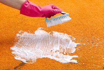 女人手清洁染色地毯硬刷橙色地毯清洁地毯清洁服务概念