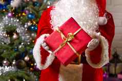 圣诞老人老人手持有红色的礼物盒子相反圣诞节树