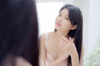 美丽的年轻的亚洲女人微笑镜子触摸头发房间化妆品卫生头发护理美亚洲女孩快乐发型治疗首页生活方式化妆概念