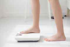生活方式活动腿女人站测量重量规模饮食光着脚特写镜头脚女孩苗条的重量损失测量食物控制营养健康的护理健康概念