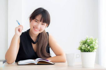 美丽的年轻的亚洲女人微笑坐着研究学习写作笔记本<strong>日</strong>记生活房间<strong>首页</strong>女孩家庭作业业务女人工作表格教育概念