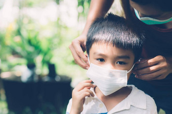 妈妈。护理儿子脸面具保护疾病流感科维德在户外妈妈穿医疗面具孩子安全保护爆发流感大流行公共医疗概念