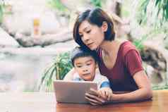 儿子数字平板电脑电脑研究学习互联网在线妈妈。教育首页家庭娱乐妈妈教男孩技术媒体生活方式概念
