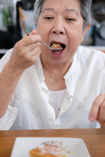 亚洲上了年纪的高级老女人吃蛋糕餐厅