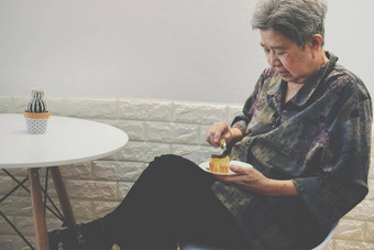 亚洲上了年纪的高级老女人吃芝士蛋糕餐厅成熟的退休生活方式