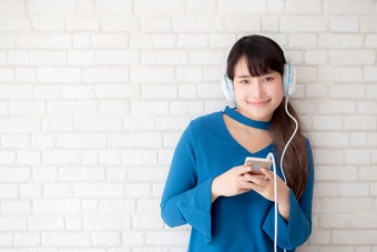 美丽的肖像亚洲年轻的女人站快乐享受有趣的听音乐耳机水泥混凝土背景生活方式女孩放松声音广播耳机技术概念
