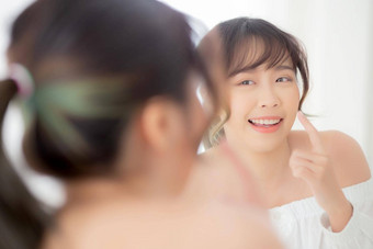 美丽的脸年轻的亚洲女人快乐微笑镜子化妆美面部女孩护肤品化妆品治疗刷新女清洁迷人的健康的概念