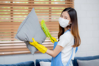 年轻的亚洲女人脸面具手套清洁灰尘除尘器沙发垫子首页女孩做家务卫生房子<strong>管家</strong>服务<strong>健康</strong>护理生活方式概念