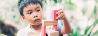 亚洲年轻的男孩玩木块玩具表格有创意的发展快乐孩子学习技能活动谜题创造力游戏桌子上首页教育概念横幅网站
