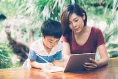 儿子数字平板电脑电脑研究学习互联网在线妈妈。教育首页家庭娱乐妈妈教男孩家庭作业技术生活方式概念