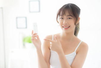 美丽的肖像年轻的亚洲女人持有指出展示奶油乳液产品美亚洲女孩显示化妆品化妆保湿皮肤护理健康的健康概念