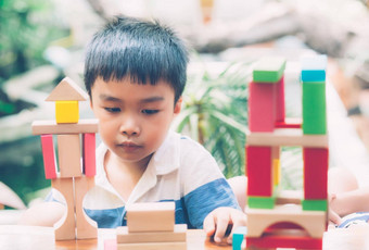 亚洲年轻的男孩玩木块玩具表格有<strong>创意</strong>的发展享受快乐孩子学习技能活动谜题创造力游戏桌子上首页<strong>教育</strong>概念