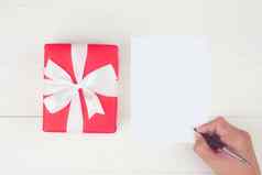 手男人。写作信空白问候卡红色的礼物盒子木表格现在包明信片模型前视图平躺复制空间假期概念
