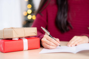 特写镜头手年轻的亚洲女人写作明信片圣诞节一天首页夏娃庆祝女写作消息问候卡给礼物盒子假期祝贺庆祝活动