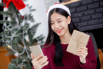 年轻的亚洲女人自拍<strong>视频</strong>调用在线朋友显示礼物盒子圣诞节一天电话首页社会距离正常的女<strong>视频</strong>会议沟通<strong>假期</strong>概念