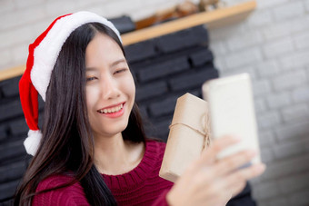年轻的亚洲女人自拍<strong>视频</strong>调用在线朋友显示礼物盒子圣诞节一天电话首页社会距离正常的女<strong>视频</strong>会议沟通<strong>假期</strong>概念