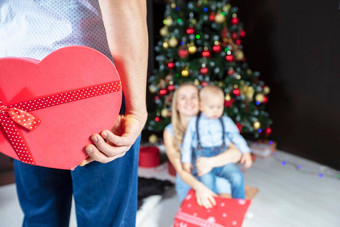 手持有红色的礼物盒子背景圣诞节树圣诞节现在家庭