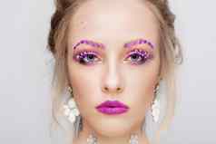 脸年轻的女孩模型紫色的化妆花俏的眉毛女人肖像关闭