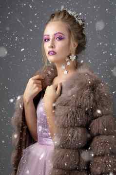 美丽的模型时尚化妆皮毛外套奢侈品冬天女孩灰色的背景散落雪