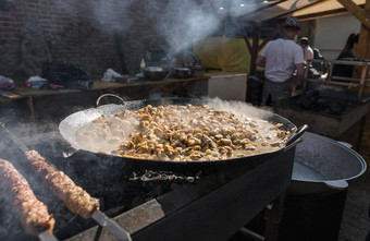 乌克兰卢茨克6月男人。烹饪新鲜的贻贝贝壳大金属烧烤锅食物党