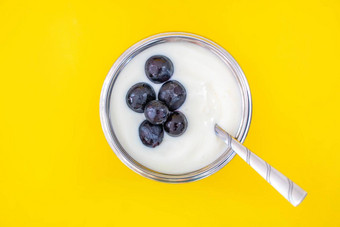 自然味道白色酸奶不锈钢钢杯不锈钢钢勺子一流的葡萄水果甜蜜的酸味道黄色的背景