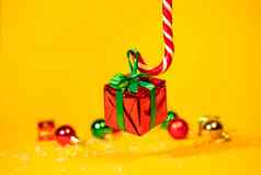 糖果狗棒棒糖持有礼物盒子圣诞节现在黄色的背景圣诞节糖果一年装饰