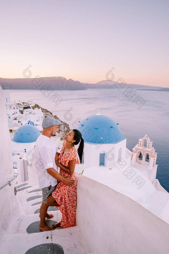 圣托里尼岛希腊年轻的夫妇奢侈品假期岛圣托里尼岛看日出蓝色的圆顶教堂白色村aio圣托里尼岛希腊