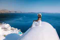 圣托里尼岛希腊年轻的女人奢侈品假期岛圣托里尼岛看日出蓝色的圆顶教堂白色村aio圣托里尼岛希腊日出但女人假期希腊