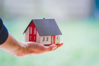 成人手持有红色的房子模型在户外概念首页财产房地产