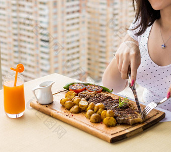 女人吃美味的牛排土豆蔬菜木板