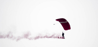 轮廓降落伞特技无重点模糊的滑翔空气红色的烟小道空气展览