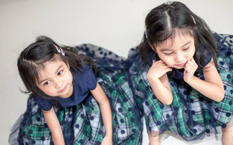 相同的双胞胎女孩姐妹摆姿势相机快乐双胞胎姐妹礼服相机微笑额视图白色背景