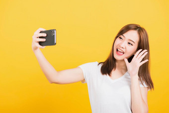 女人青少年微笑站穿t恤使自拍照片视频调用智能手机