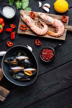 西班牙语西班牙海鲜饭成分大米虾墨鱼贻贝黑色的木表格前视图