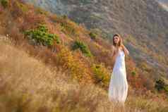 美丽的纤细的女孩白色衣服背景美丽的山景观
