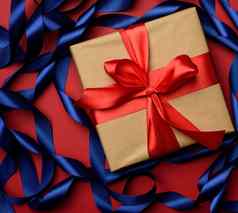 广场礼物盒子包装棕色（的）纸卷蓝色的丝绸丝带红色的背景