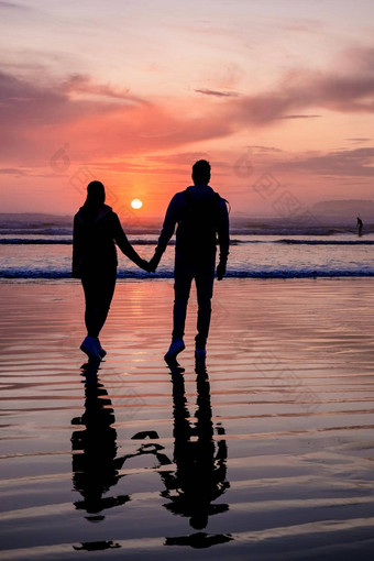 夫妇但女人中期年龄看日落海滩tofino温哥华岛加拿大美丽的日落海滩粉红色的紫色的颜色天空