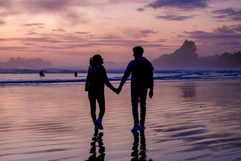 夫妇但女人中期年龄看日落海滩tofino温哥华岛加拿大美丽的日落海滩粉红色的紫色的颜色天空