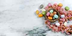 快乐复活节假期概念鸟巢色彩斑斓的鸡蛋粉红色的樱桃开花花石头背景平躺格式