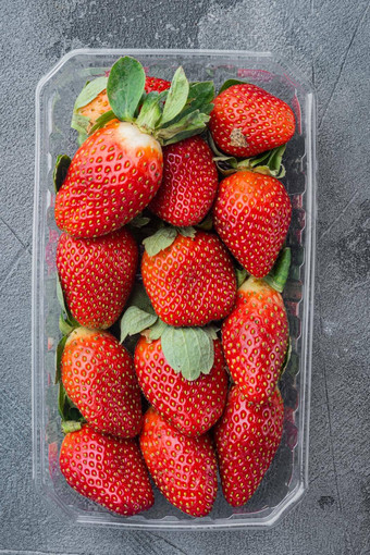 透明的塑料托盘新鲜选草莓灰色的背景前视图平躺