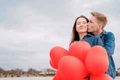 年轻的爱的夫妇红色的气球拥抱接吻在户外
