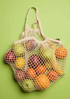 成熟的新鲜的水果纺织字符串袋绿色背景