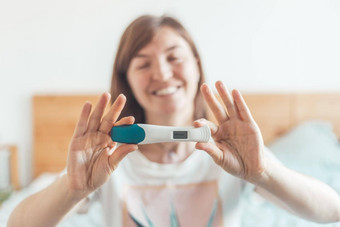 快乐女人坐着床上检查怀孕测试结果积极的怀孕