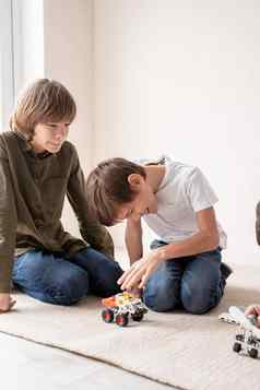 年轻的男孩有趣的构建机器人汽车坐着地毯