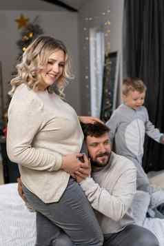 快乐家庭概念丈夫拥抱肚子怀孕了妻子站室内生活房间沙发