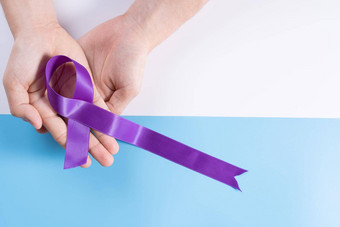 世界癌症一天手持有紫色的丝带蓝色的背景复制空间文本医疗保健医疗概念