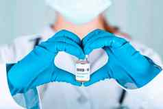 女人医生护士统一的手套穿脸面具保护实验室持有形式心医学瓶疫苗瓶科维德coronovirus疫苗标签