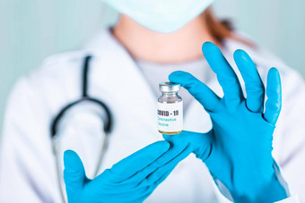女人医生护士统一的手套穿脸面具保护实验室持有医学瓶疫苗瓶科维德coronovirus疫苗标签