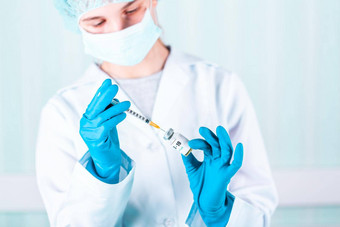 女人医生护士统一的手套穿脸面具保护实验室持有医学瓶疫苗瓶科维德coronovirus疫苗标签