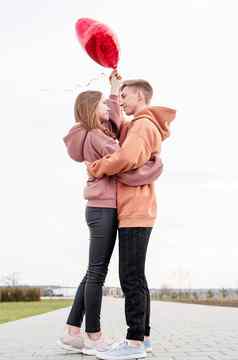 年轻的爱的夫妇红色的气球拥抱在户外有趣的